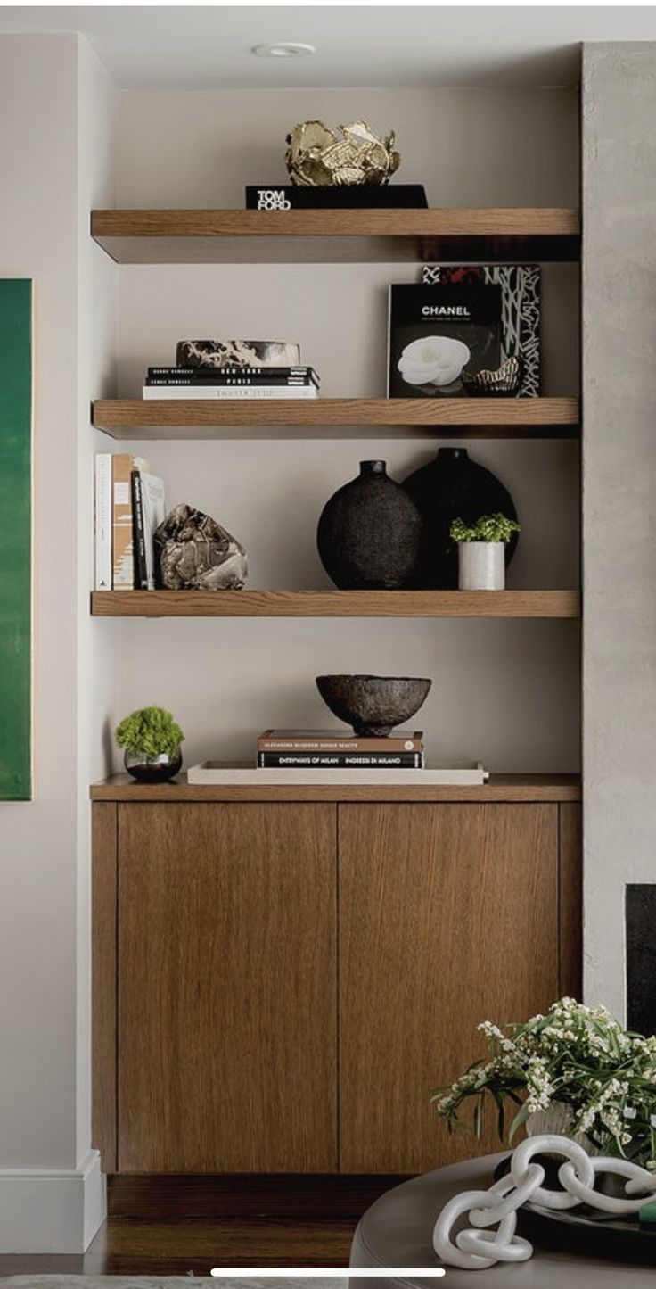 a living room filled with lots of shelves next to a wall mounted painting on the wall