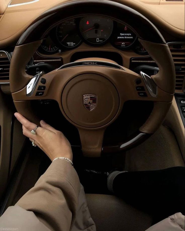 a woman driving a car with her hand on the steering wheel and dashboard controls in front of her