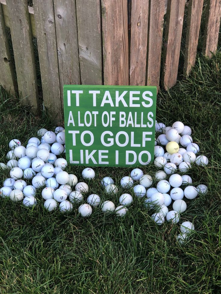 a pile of golf balls sitting in the grass next to a sign that says it takes alot of balls to golf like i do