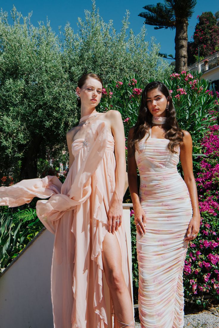 two women standing next to each other in dresses