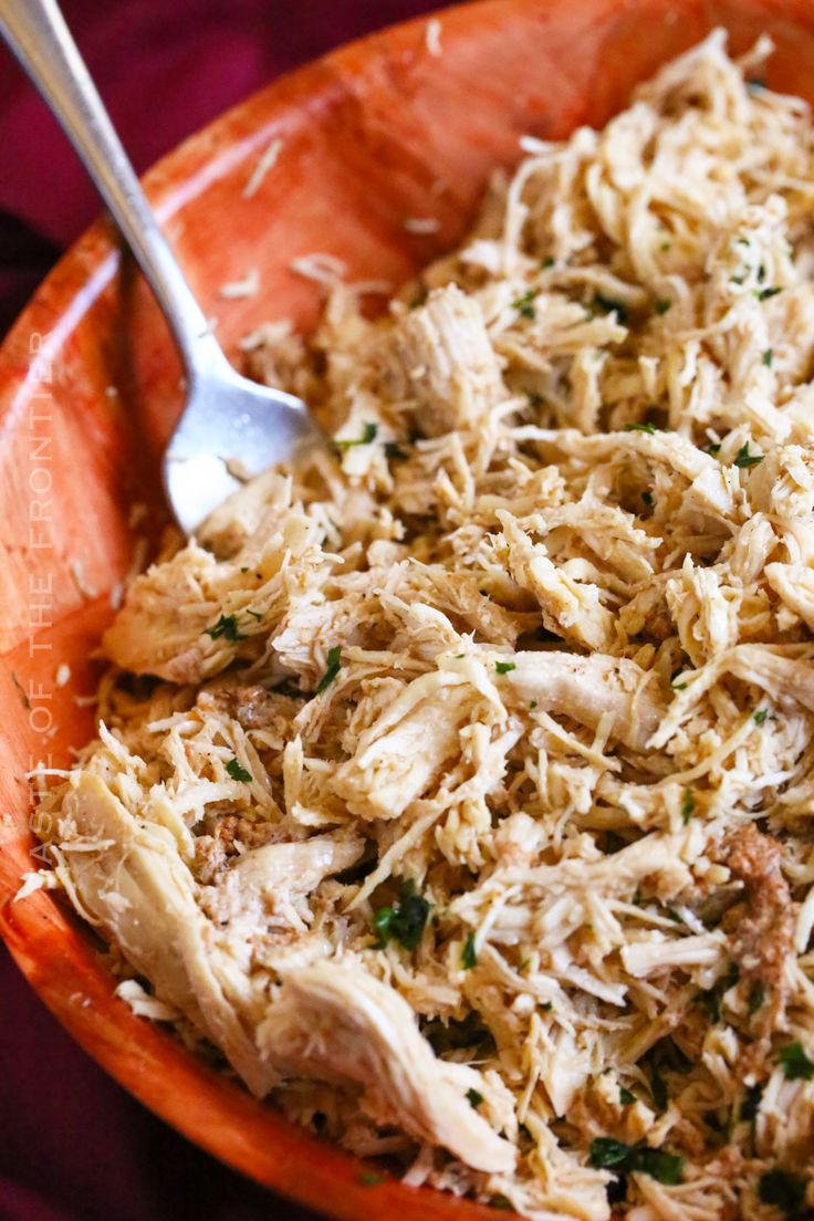 shredded chicken in an orange bowl with a spoon