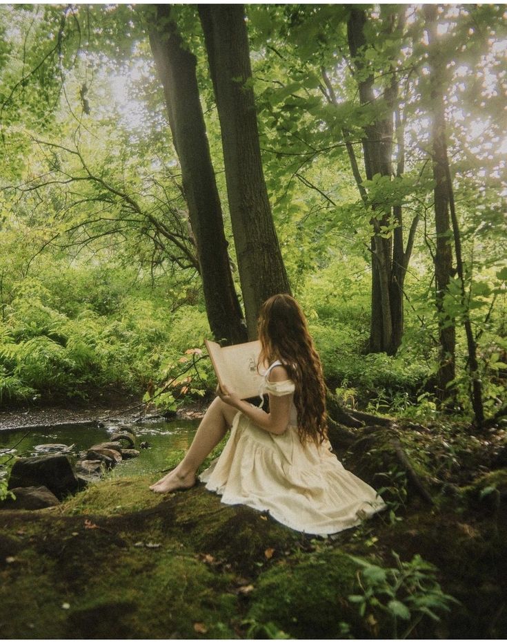 a woman sitting in the woods reading a book