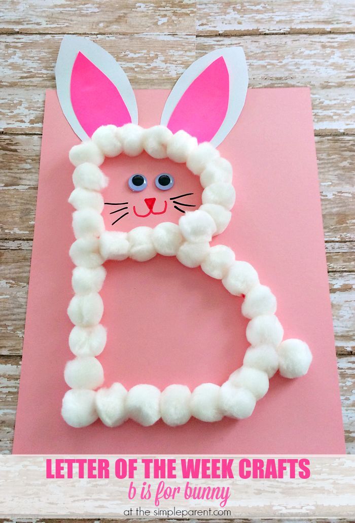 the letter e made out of paper and yarn with bunny ears on it, sitting on top of a pink sheet of paper