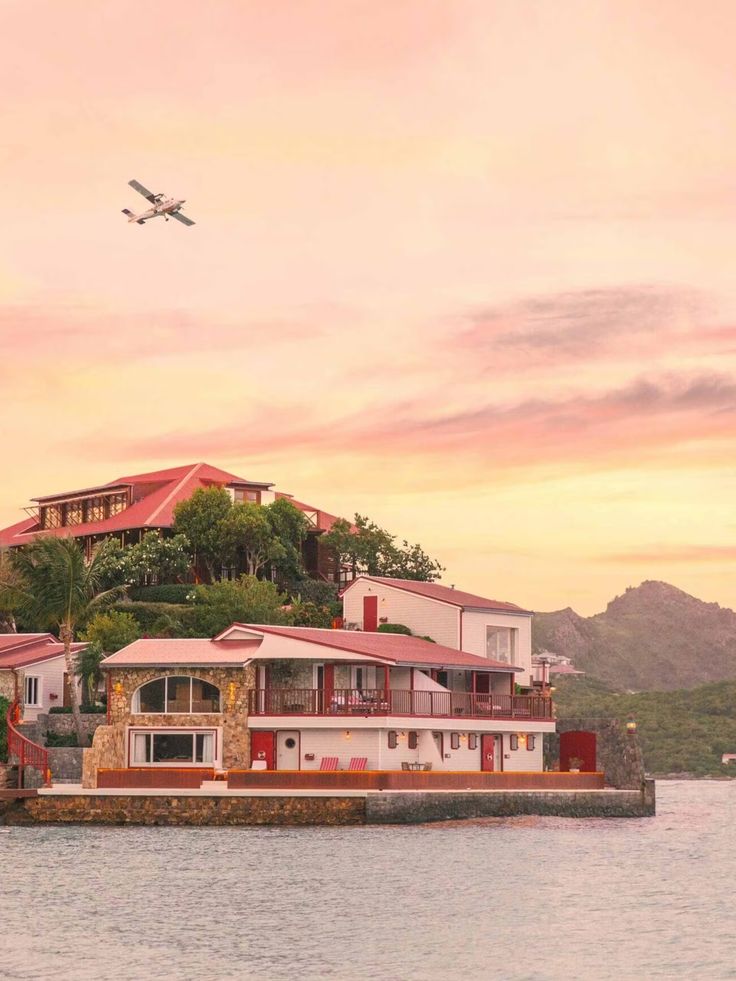 an airplane is flying over a house on the water