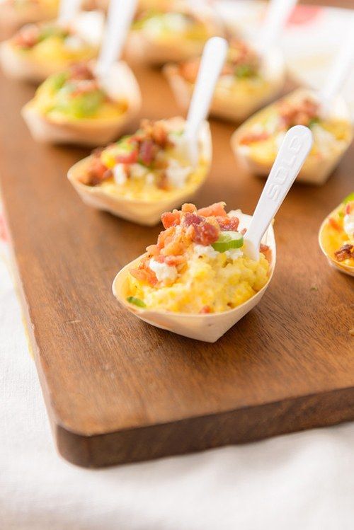 small cups filled with food sitting on top of a wooden tray