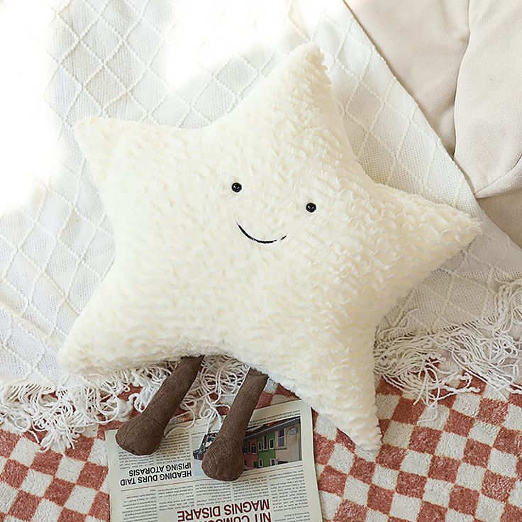 a white star pillow sitting on top of a red and white checkered blanket