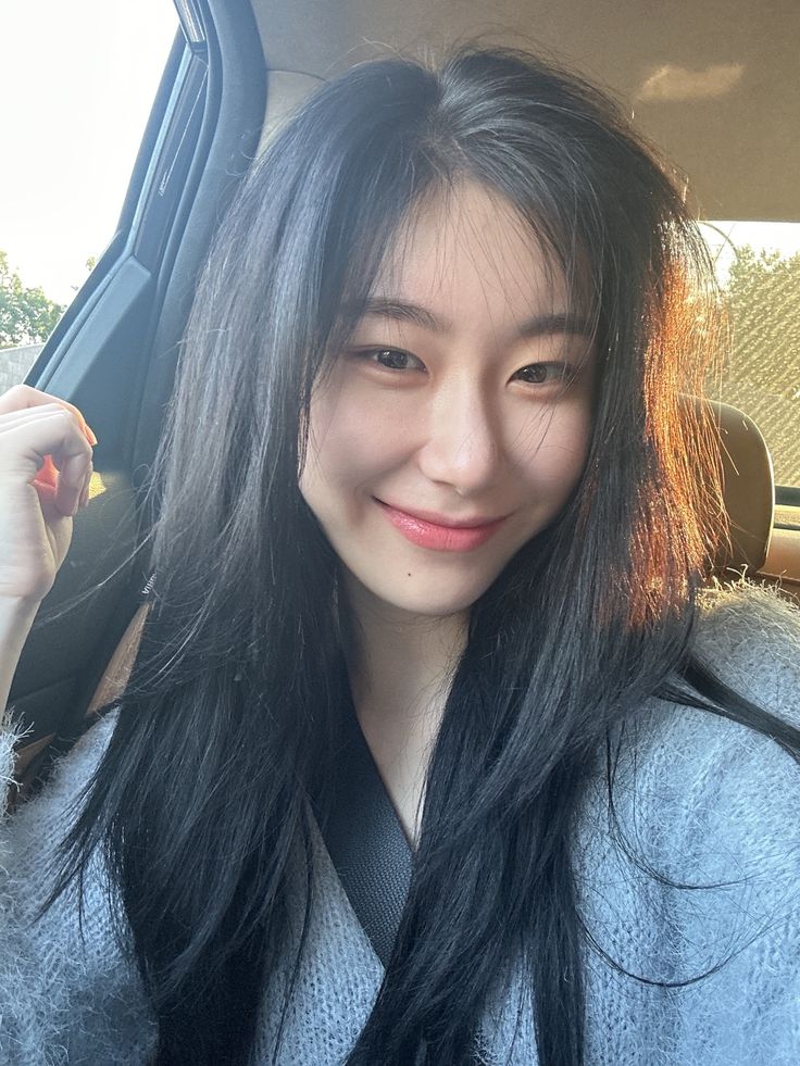 a woman with long black hair sitting in the back seat of a car and smiling