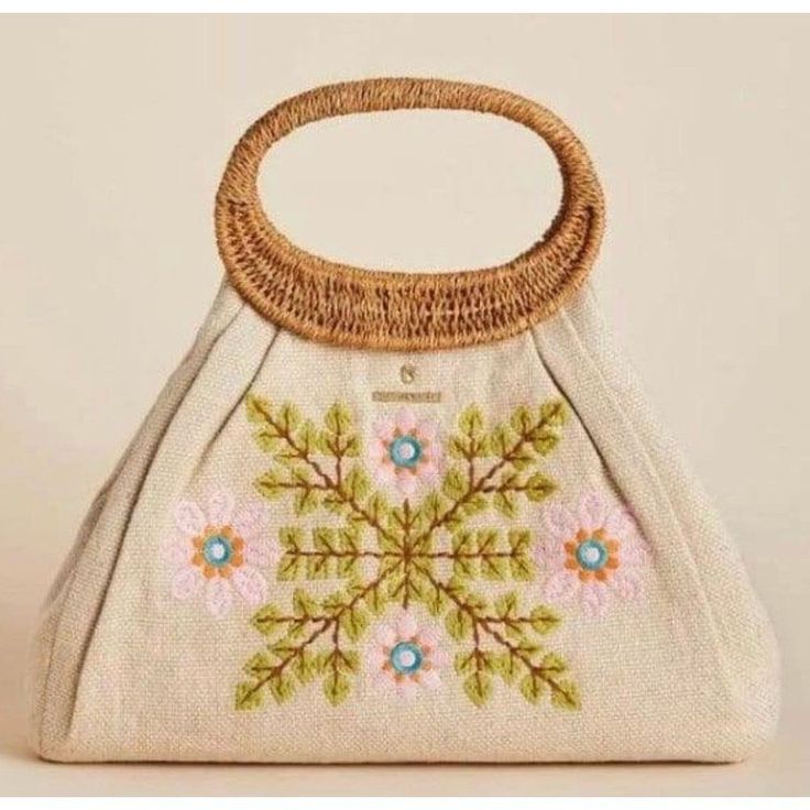 a white purse with flowers on it and a handle that is made out of woven material