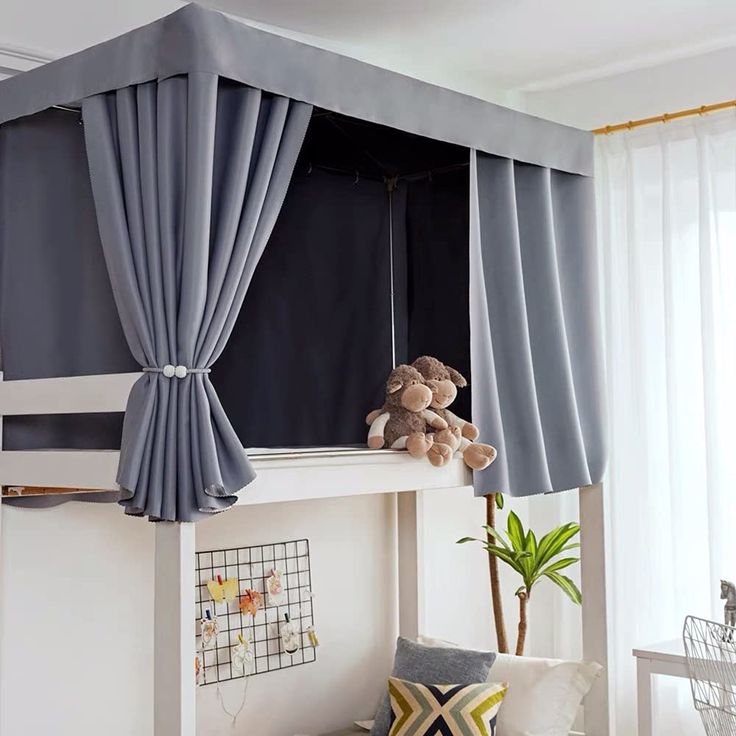 a child's loft bed with curtains on the side and a teddy bear sitting on top