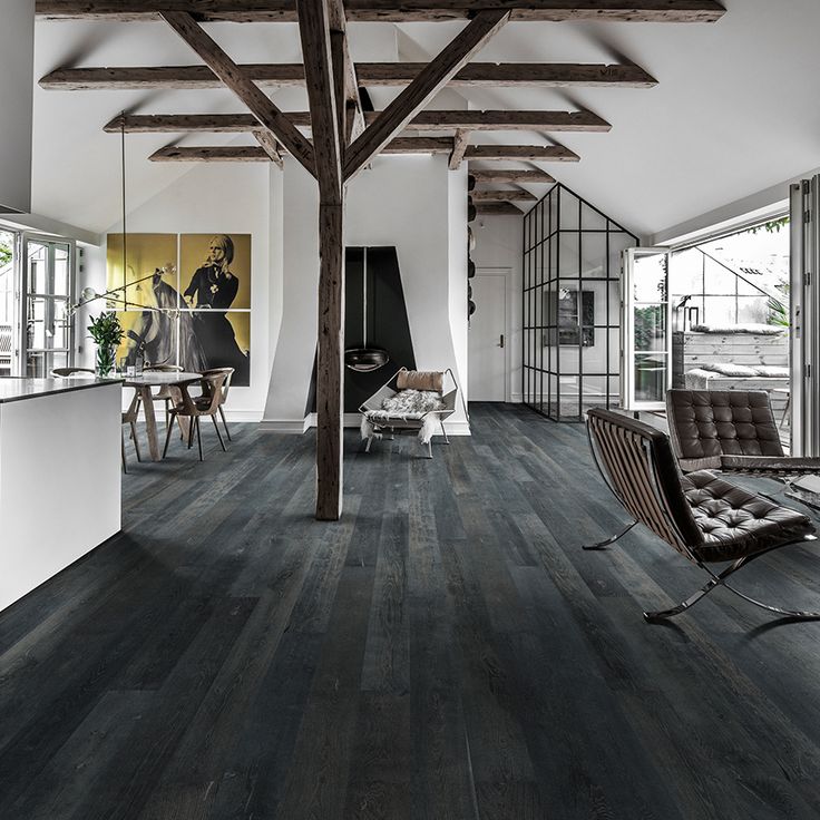 a living room filled with furniture and wooden beams on the ceiling, along with windows