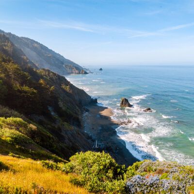 a scenic view of the ocean and mountains from a hill side trail in big sur, california