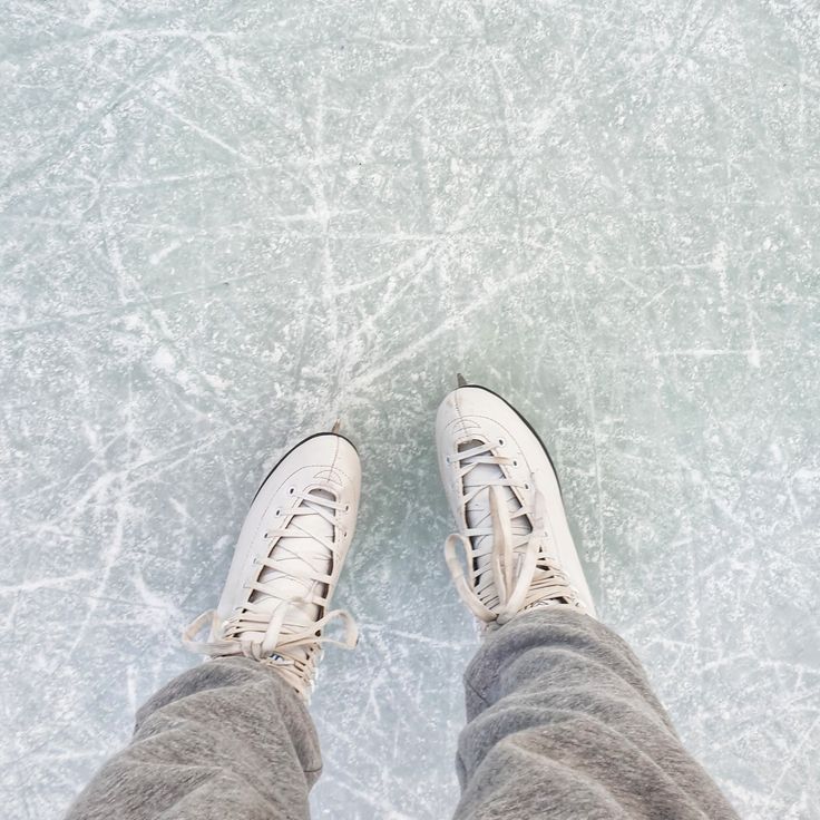 a person standing on an ice rink with their feet in the air and wearing white sneakers