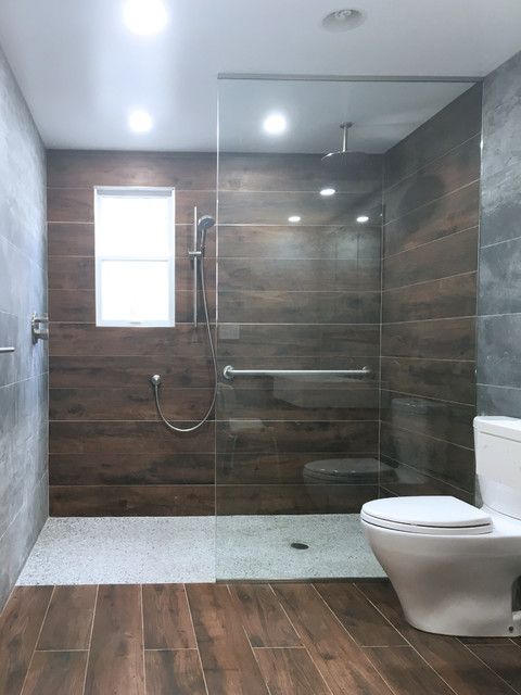 a modern bathroom with wood flooring and glass shower door, along with a toilet