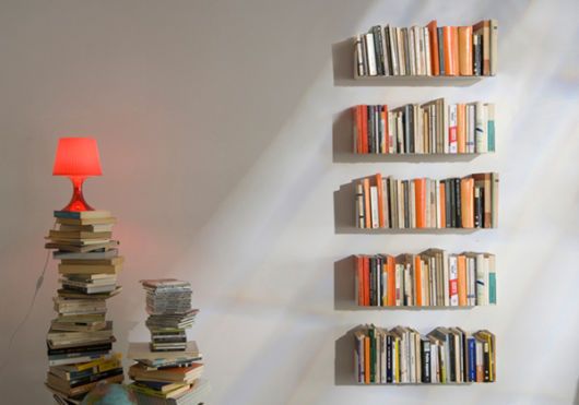 a room with books on the shelves and a lamp next to it in front of a white wall