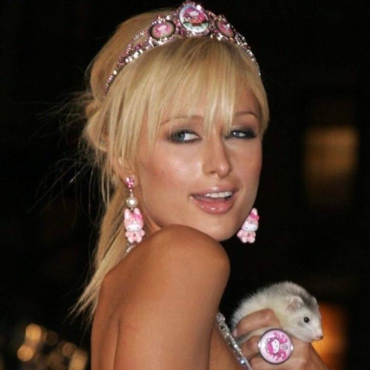 a woman in a tiara holding a baby hedgehog wearing pink flowers and pearls