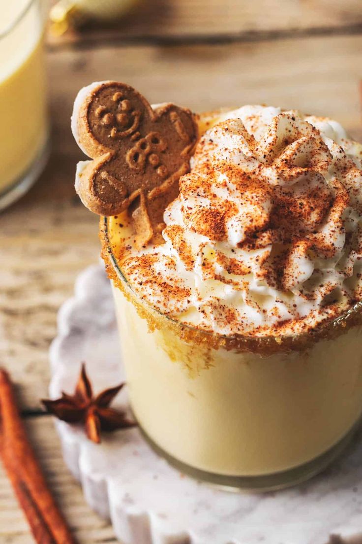 a cup filled with cinnamon and topped with whipped cream, ginger cookies and star anisette