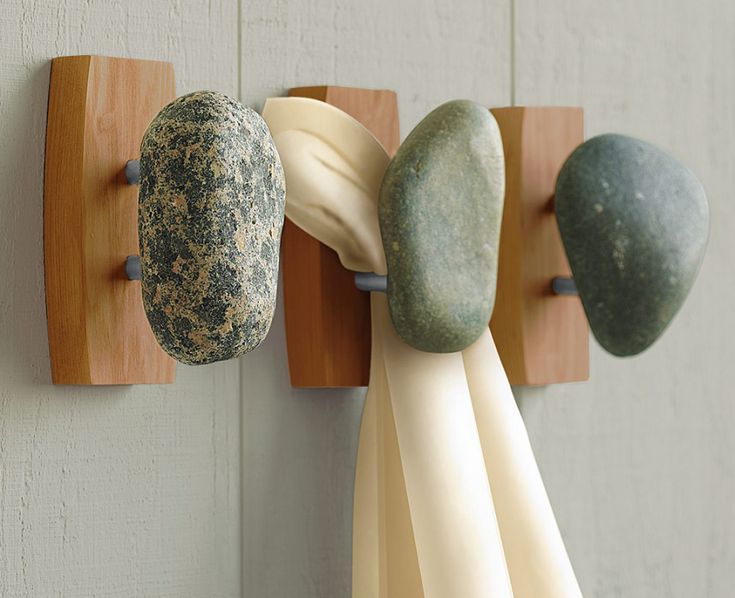 three different colored rocks hanging from hooks on a wall