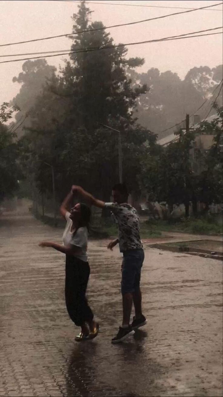 two people are playing in the rain on their skateboards