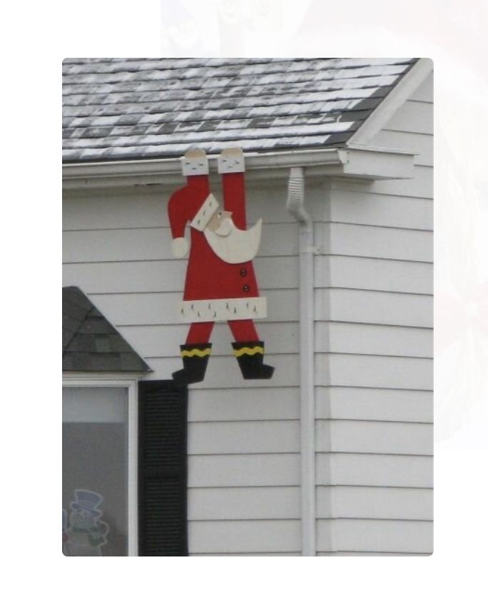 a christmas decoration hanging from the side of a house in front of a white building