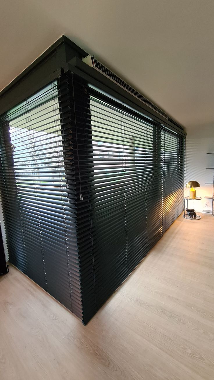 an empty room with wooden floors and large blinds