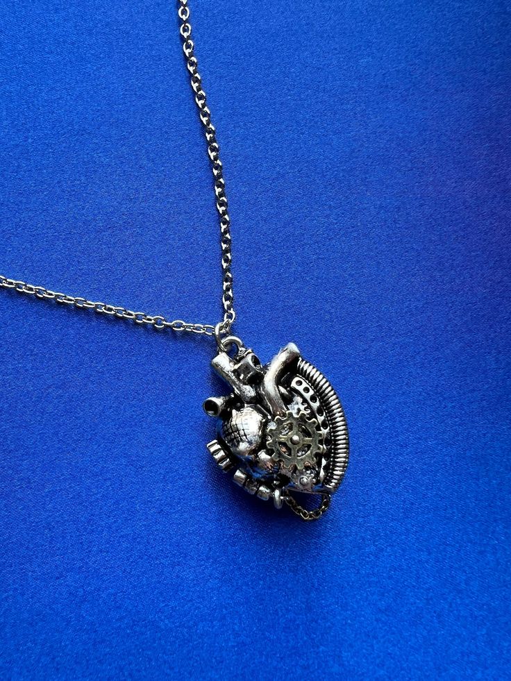 Be sentimental in style with new jewelry from Cosmic Created Magic! This steampunk heart locket necklace is a great gift for your goth girlfriend. Hanging from an 18 inch silver necklace is a steampunk heart picture locket with heart valves, gears, cogs, and knobs. Open the locket and add a photo of someone you like to keep close to your heart. You're sure to stand out with such a cool, unique locket. Punk Necklace With Lobster Clasp As Gift, Punk Style Nickel-free Necklace For Gifting, Punk Style Metal Heart Pendant Necklace, Punk Style Heart Pendant Jewelry With Heart Charm, Punk Style Metal Necklace With Heart Pendant, Punk Metal Heart Necklace For Valentine's Day, Punk Style Metal Heart Necklace For Valentine's Day, Silver Punk Heart Pendant Jewelry, Punk Style Heart Charm Necklace As Gift