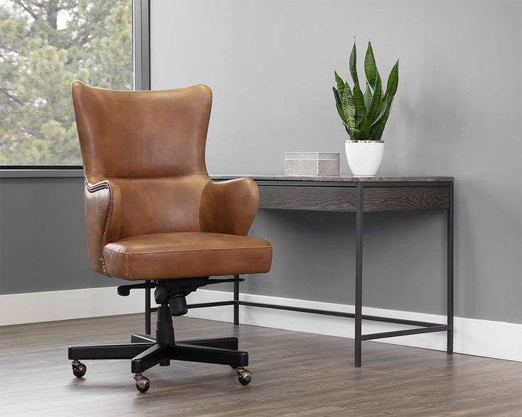 a brown leather office chair sitting in front of a desk with a potted plant