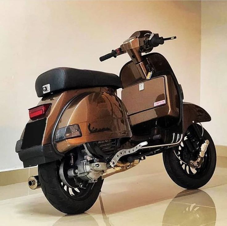 a brown motorcycle parked in a room with white walls