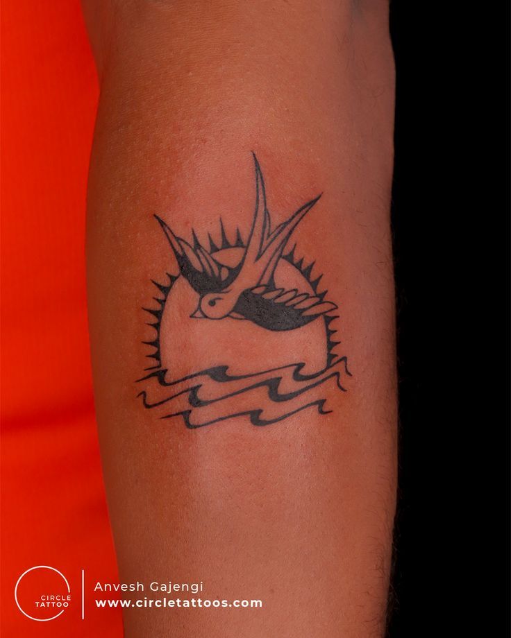 a tattoo on the arm of a person with a bird and sun in the background