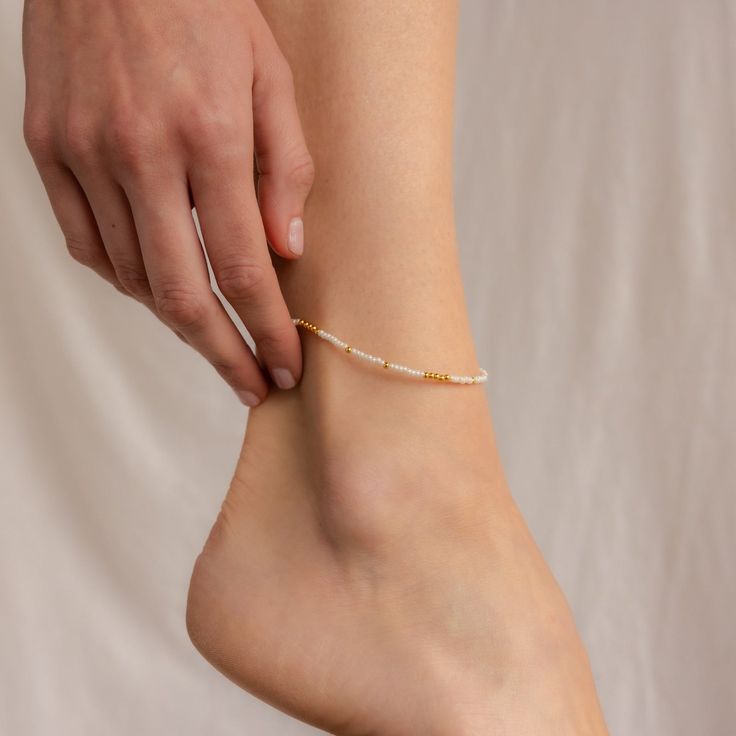 Get ready to dance with joy wearing our Dainty Pearl Beaded Anklet. This playful accessory, embellished with tiny pearls, brings a sprinkle of magic and whimsy to your summer adventures. Whether you’re wandering along sandy shores or twirling in a boho garden, this anklet adds a touch of fairy-tale charm to your ensemble. Material: High Quality Solid 925 Sterling Silver Finish: Sterling Silver ∙ 18K Gold Featuring ~2mm White & Gold or White & Silver Beads across the anklet. Anklet length is adju Adjustable Gold Beads Anklets, Summer Gift Anklets With Gold Beads, White Beaded Chain Anklets As Gift, White Beaded Chain Anklets For Gift, Adjustable White Anklets For Spring, White Tiny Beads Anklets For Festival, Adjustable Pearl Anklets For Summer, Delicate White Adjustable Anklets, Summer White Pearl Anklets