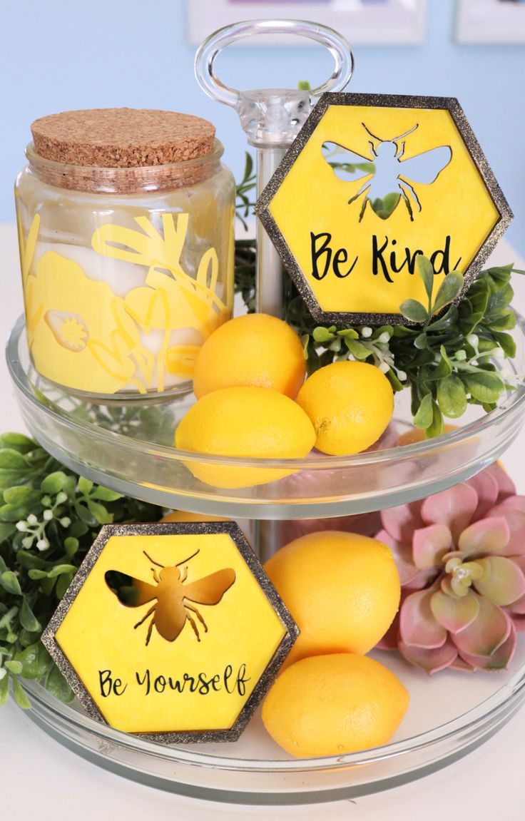 three tiered tray with lemons, honey and bees on it that says be kind