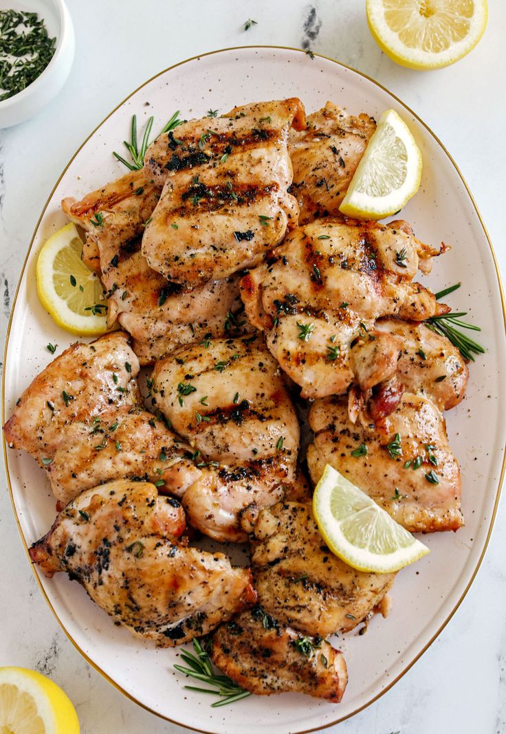 grilled chicken with lemons and herbs on a white plate