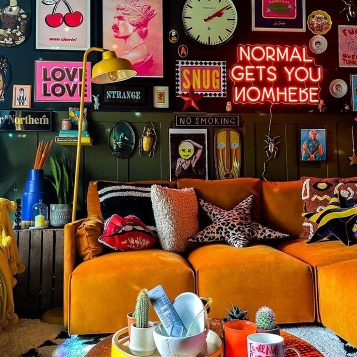 a living room filled with orange couches and lots of pictures on the wall above them