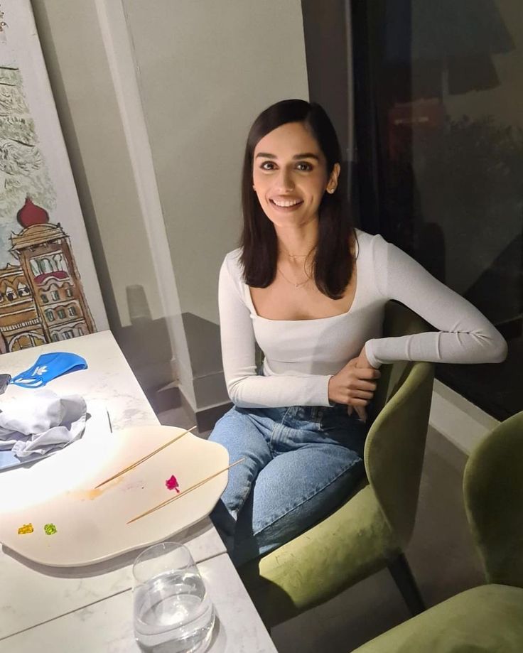 a woman sitting at a table in front of a surfboard