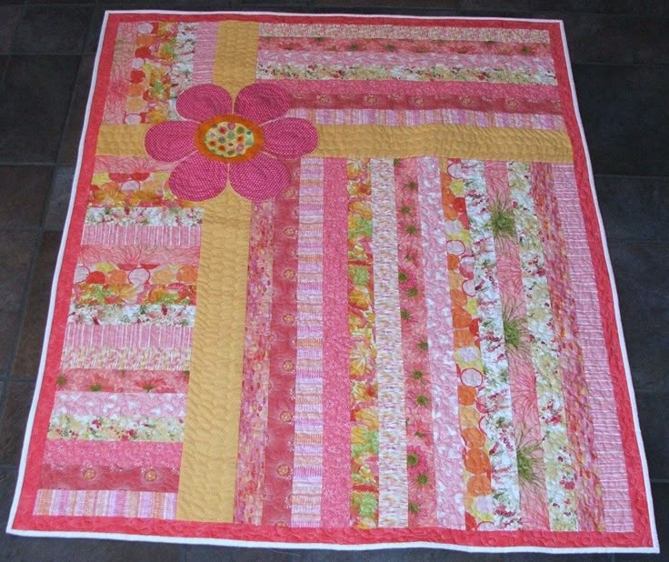 a pink and yellow quilt with flowers on it