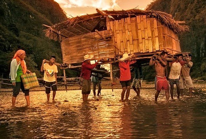 a group of people standing on top of a river next to a wooden structure in the water