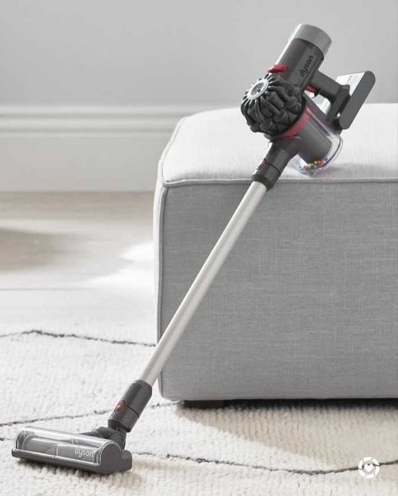 a close up of a vacuum cleaner on the floor in front of a white couch