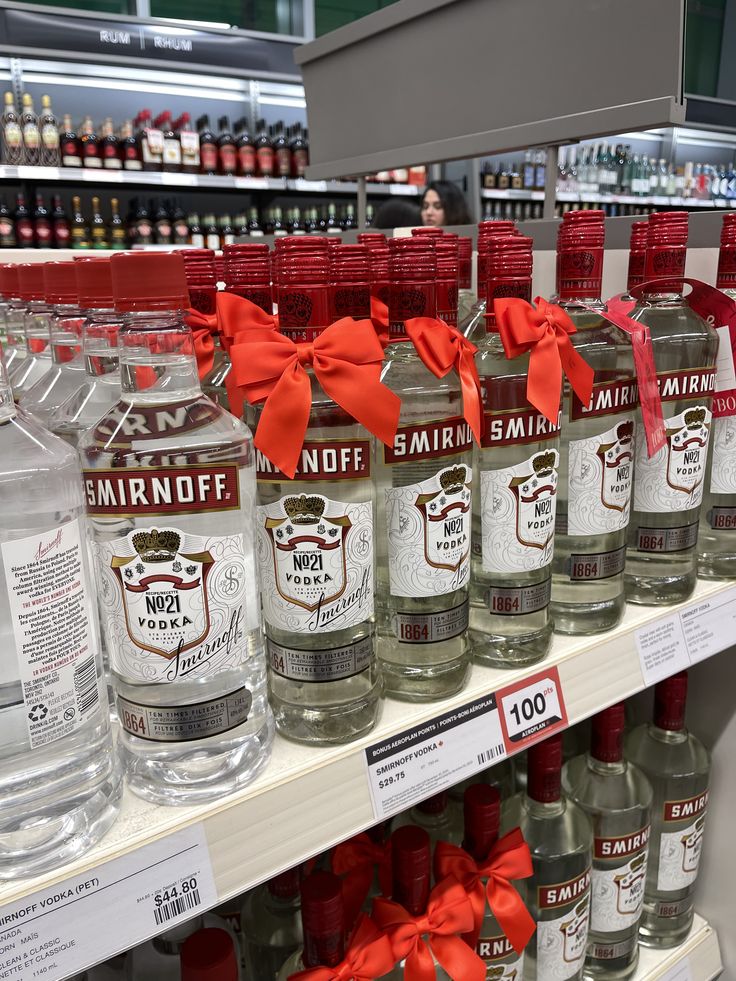 many bottles of alcohol are on display in a liquor store, with red bows tied around them