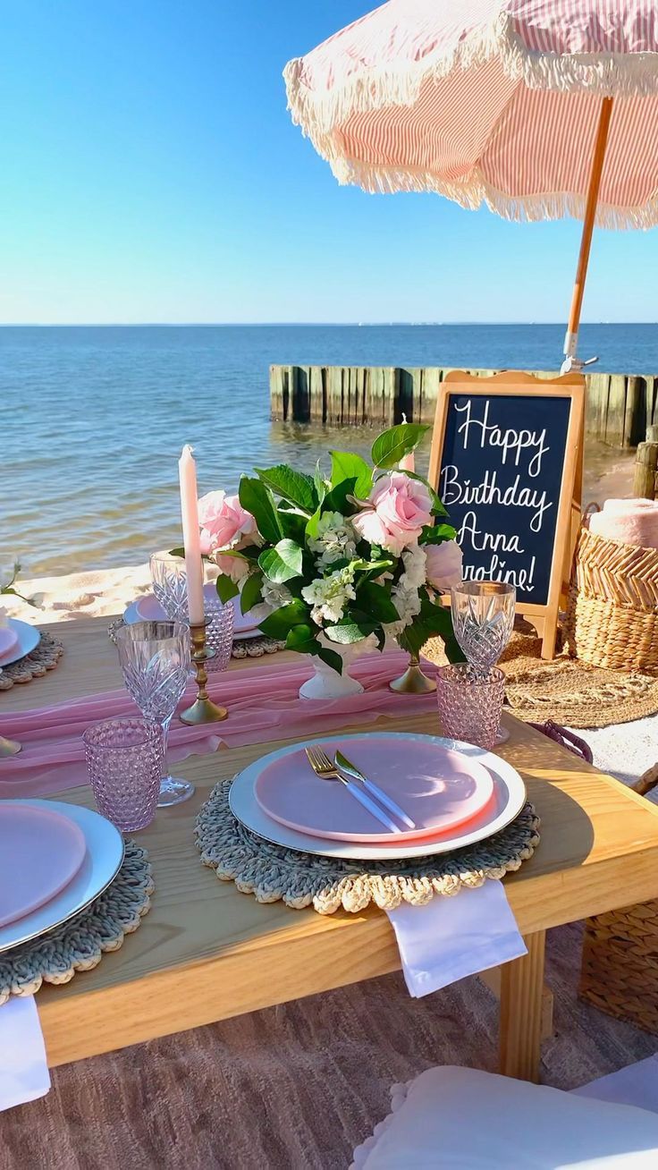 the table is set with plates and place settings for an outdoor birthday party on the beach