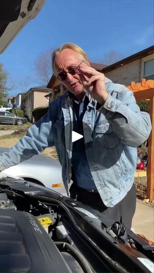 an older man standing next to a car looking under the hood