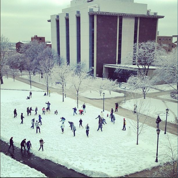 many people are walking through the snow in front of a building