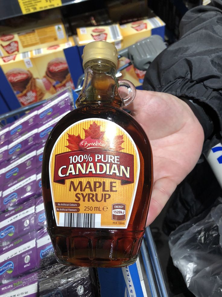 a bottle of maple syrup is being held by someone's hand in a store