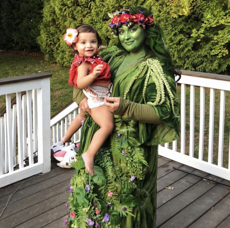 a woman holding a child in her arms while standing on a porch next to a statue