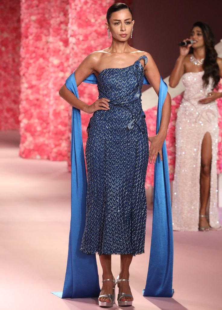 a model walks down the runway in a blue dress