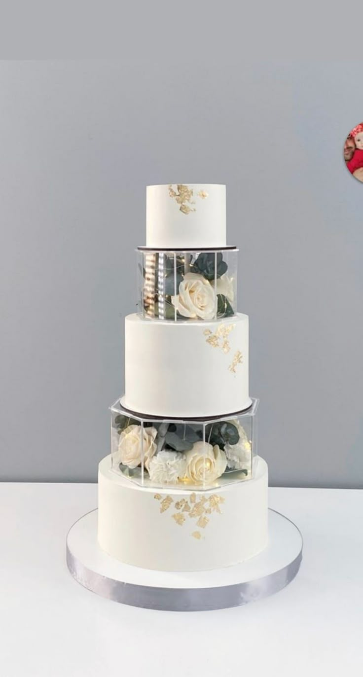 a three tiered white cake with gold flowers on the top and bottom, sitting on a silver platter