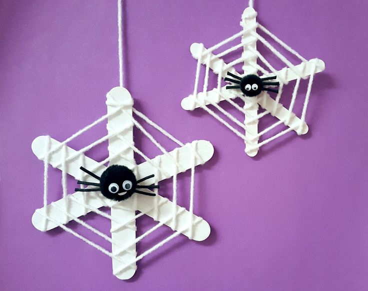 two paper snowflakes with black cats on them hanging from strings against a purple wall