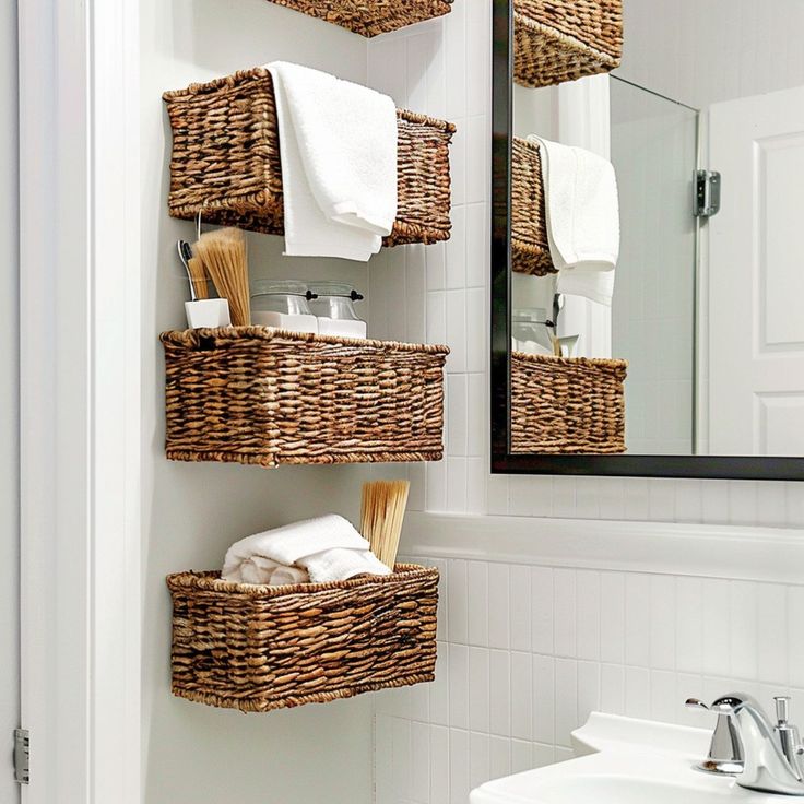 a bathroom with wicker baskets on the wall and a mirror in the corner above it