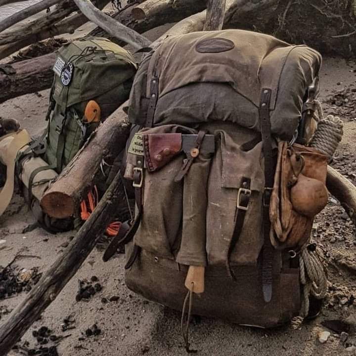 an old backpack sitting on the ground next to some logs and other items that have been placed around it