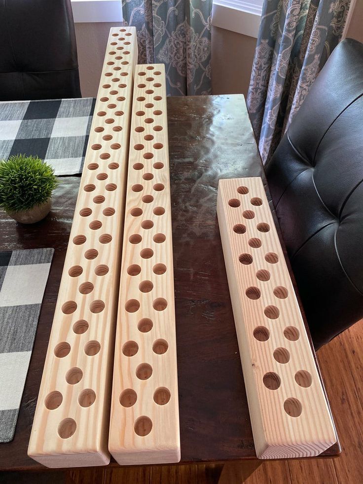 three peg boards sitting on top of a wooden table next to a potted plant