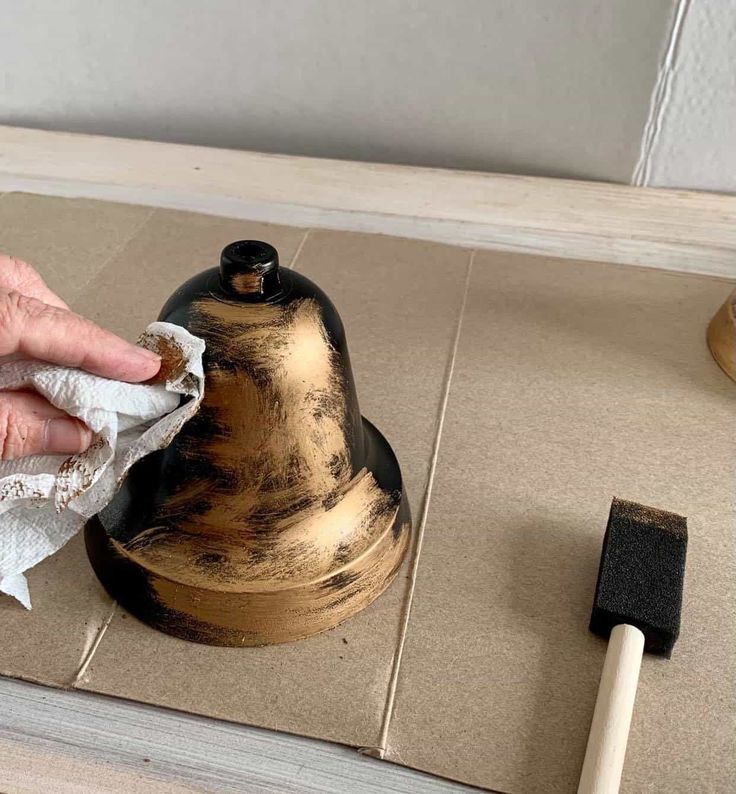 a person wiping up some paper on top of a wooden table next to a bell