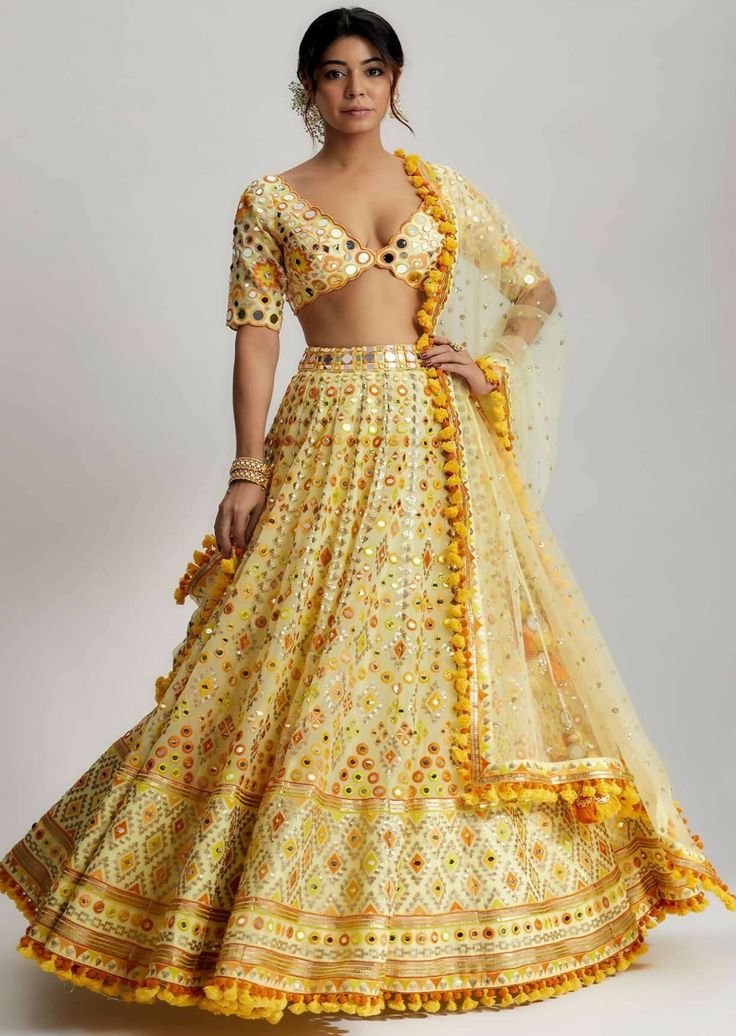 Adorned with playful pompoms and tassels, the anha lehenga exudes a playful charm. These charming embellishments add a whimsical element to the ensemble, enhancing its overall appeal. The carefully selected fabric drapes gracefully, accentuating the beauty of the wearer and creating a regal silhouette. Festive Sharara With Tassels And Traditional Drape, Festive Traditional Drape Sharara With Tassels, Bohemian Sharara With Gota Work For Reception, Navratri Party Sets With Latkans, Party Sets With Latkans For Navratri, Festive Party Sets With Latkans, Anarkali Dress With Tassels For Navratri, Festive Sharara With Tassels For Reception, Traditional Saree Sets With Tassels